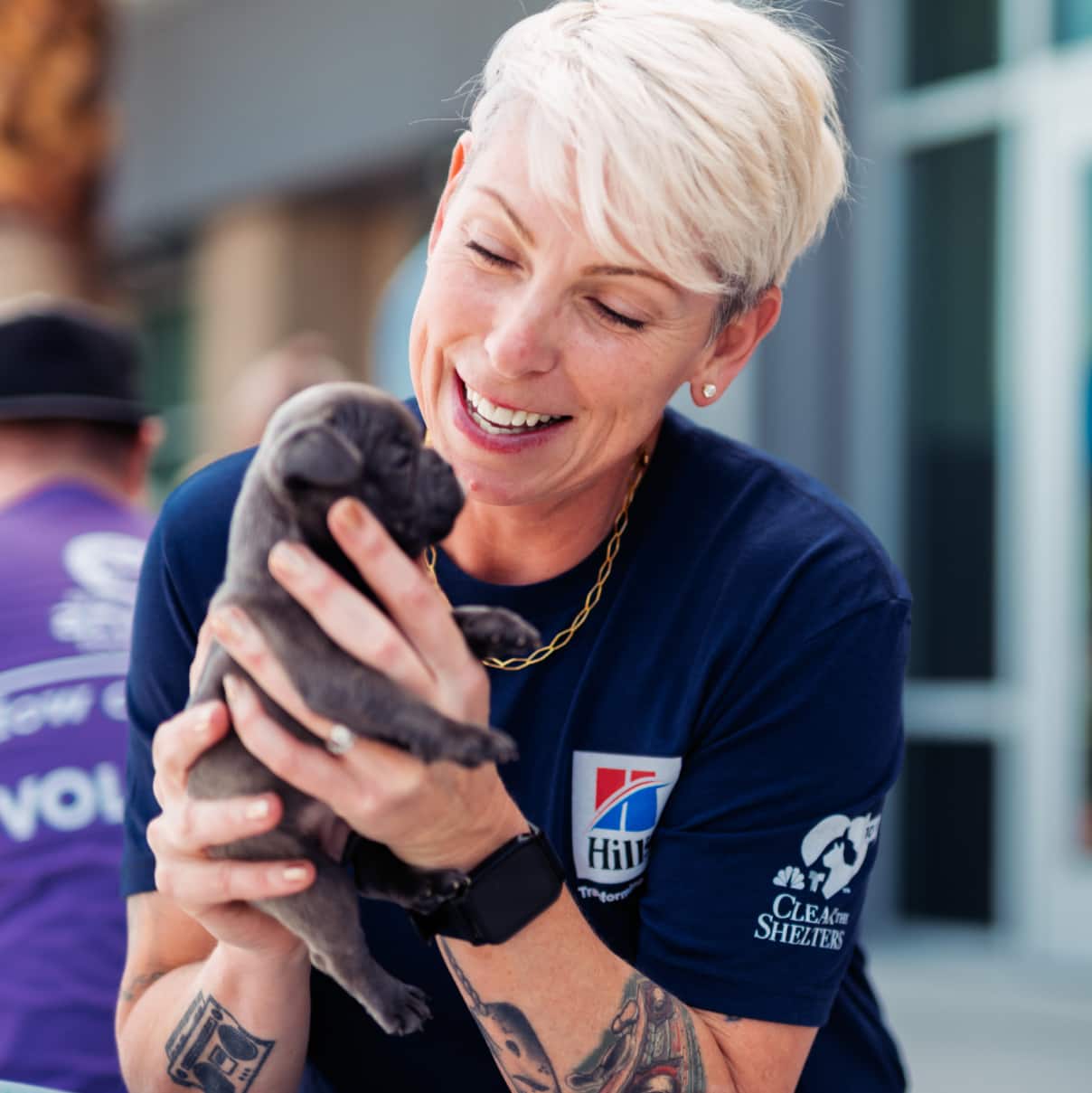 Une femme tenant un chiot gris